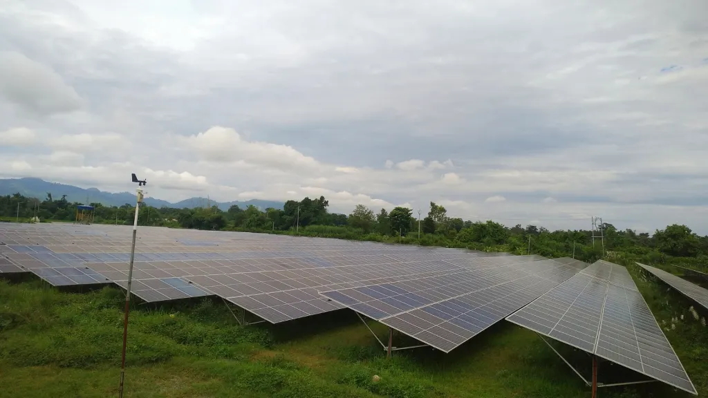 Aerial view of solar panel rows at the Chandranigapur 4 MW Solar PV Project, with a weather station mast in the foreground